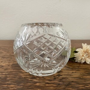 May include: A clear glass vase with a diamond pattern. The vase is round and has a wide opening.