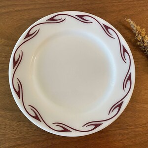 May include: White ceramic dinner plate with a maroon floral design around the rim.