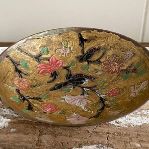 以下が含まれることがあります： 金色の仕上げが施された、小さな丸い真鍮製のボウル。ボウルは、黒、緑、ピンク、赤のエナメルで花と鳥のデザインが施されています。