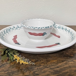 May include: White ceramic serving dish with a smaller bowl in the center. Both pieces feature a green and white speckled glaze and red pepper designs.