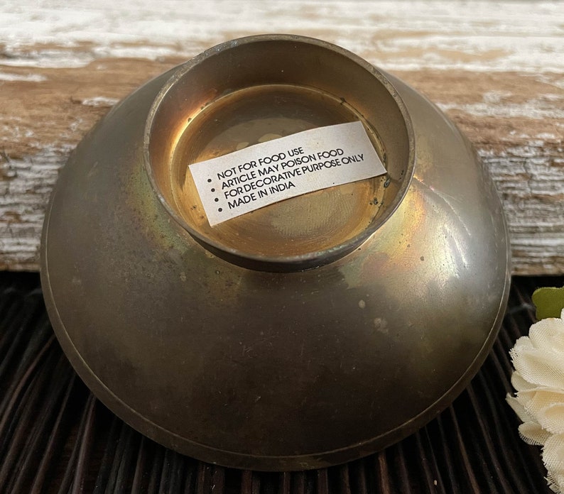 以下が含まれることがあります： 「NOT FOR FOOD USE ARTICLE MAY POISON FOOD FOR DECORATIVE PURPOSE ONLY MADE IN INDIA」とラベルが付いた真鍮製のボウルです。