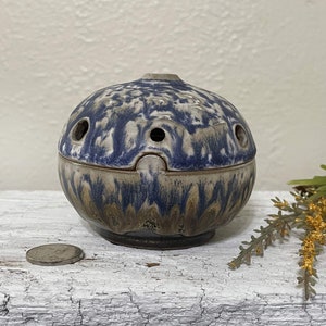 May include: A blue and white ceramic incense burner with a lid. The burner has a speckled glaze and a round shape. It has several small holes in the top for incense to burn.