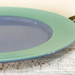 May include: A blue and green ceramic plate with a raised rim. The plate has a light blue center and a green outer rim.