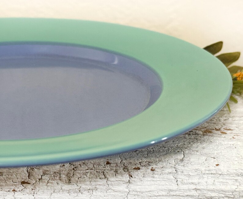 May include: A blue and green ceramic plate with a raised rim. The plate has a light blue center and a green outer rim.