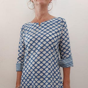 Peut inclure: Une robe à motif bleu et blanc avec un col rond et des manches trois-quarts. Les manches ont des rayures blanches sur les poignets.