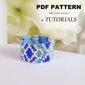 May include: A beaded ring in shades of blue and silver, with a geometric pattern. The ring is the focal point, with text above that reads "PDF PATTERN" and "+ TUTORIALS". The ring is on a white surface.