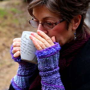 May include: Purple and blue knitted fingerless gloves with a fuzzy trim. The gloves are worn by a person holding a white mug with handwritten text that reads "Sis, I never seem to find enough time... Her and I just... no let you know overall you are..."