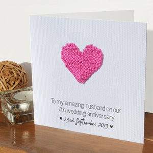May include: A white card with a pink knitted heart and the text "To my amazing husband on our 7th wedding anniversary &hearts; 23rd September 2013 &hearts;".