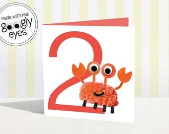 May include: A red and orange card with the number 2 and a red and orange crab with googly eyes. The card says "Made with real googly eyes".
