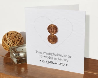 May include: A white card with a heart shape made of dotted lines. Two copper coins are placed inside the heart. The card reads "To my amazing husband on our 8th wedding anniversary ♥ 23rd September 2012 ♥".
