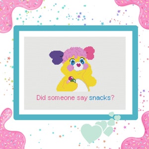 May include: A yellow Care Bear with pink and purple bows in its hair, holding a pink lollipop. The Care Bear is smiling and the text "Did someone say snacks?" is below the bear.
