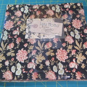 May include: A fabric bundle featuring a floral pattern in shades of pink, cream, and gold on a black background. The fabric is packaged in clear plastic with a tag that reads "Luna Notte 3 Sisters moda."
