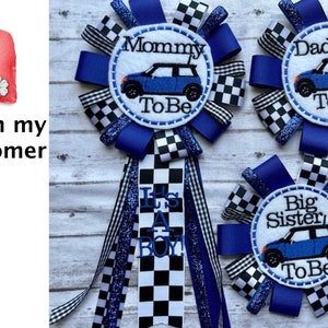 May include: Three blue and white checkered ribbon rosettes with a white circle in the center. The circles have blue embroidery that reads "Mommy To Be", "Daddy To Be", and "Big Sister To Be". Each circle also has a blue miniature car graphic.