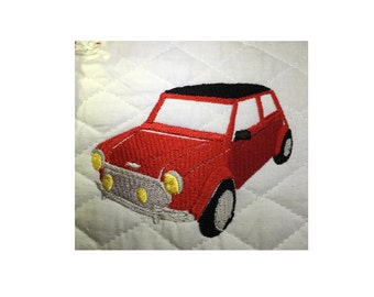 May include: Embroidered red car with a black roof, yellow headlights, and a silver grill. The car is set against a white quilted background. The wheels are black and gray.
