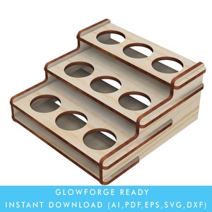 Könnte beinhalten: Ein dreistufiges Holzregal mit neun runden Aussparungen, entworfen, um kleine Flaschen oder Gläser zu halten. Das Regal ist aus hellem braunem Holz mit einer rötlich-braunen Beize an den Rändern. Das Regal ist nach rechts geneigt, wobei die oberste Stufe im Vordergrund sichtbar ist.