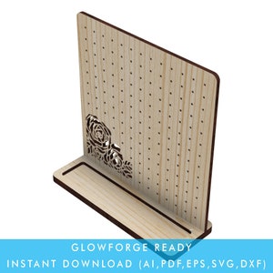 May include: A wooden earring display stand with a floral design cut out. The stand has a small shelf at the bottom and a large backboard with holes for holding earrings.