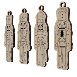 May include: Four wooden nutcracker ornaments with black outlines. The ornaments are in different sizes and feature different designs, including a drum, a sword, and a crown.
