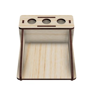 May include: Wooden organizer with three slots for pens or pencils and a larger compartment below. The organizer is made of light wood with a dark brown stain around the edges.