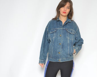 May include: A woman wearing a blue denim jacket, black leggings with a blue and pink stripe down the side, and black knee-high boots.