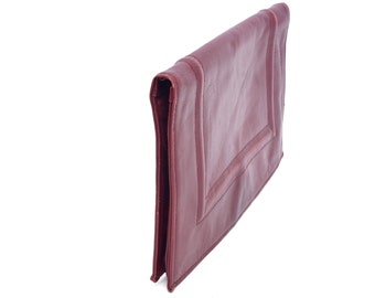 May include: A burgundy leather clutch purse with a decorative stitched design.