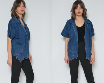 May include: A denim jacket with short sleeves and a floral design on the hem. The jacket is a dark blue color and has a collar. The model is wearing black leggings and heels.