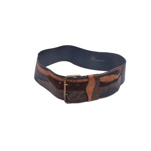 May include: A wide, brown leather belt with a patchwork design. The belt features various shades of brown leather, including a textured ostrich pattern, and a brass buckle. The belt is approximately 4 inches wide.