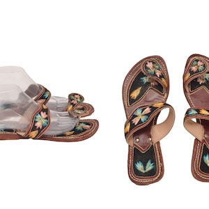 May include: A pair of brown leather sandals with colourful embroidered straps. The sandals have a pointed toe and a flat sole.
