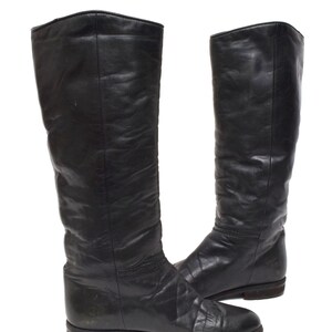 May include: A pair of black leather knee-high boots with a flat heel.