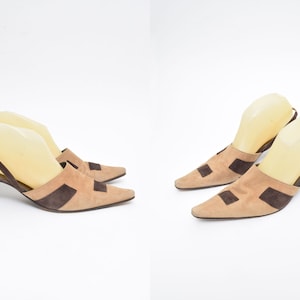 Op de afbeelding: Een paar bruine suède slingback hakken met een spitse neus en een kleine blokhak. De hakken hebben bruine suède panelen op de wreef en een slingback band.