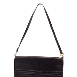May include: A black leather shoulder bag with a long strap and a decorative design on the front.