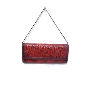 May include: A red woven leather clutch bag with a silver chain strap.