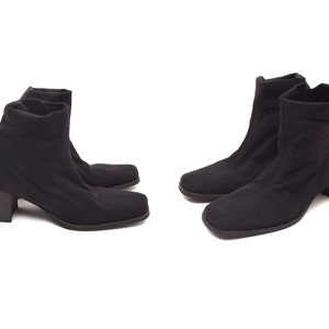May include: A pair of black ankle boots with a low block heel. The boots are made of a stretchy fabric and have a pointed toe.
