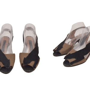 Puede incluir: Un par de sandalias de tacón negras y marrones con un diseño de silueta de gato. Las sandalias tienen la punta abierta y la parte trasera abierta.