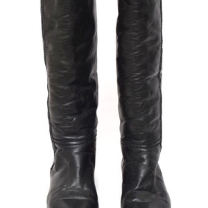 May include: A pair of black leather knee-high boots with a pointed toe.