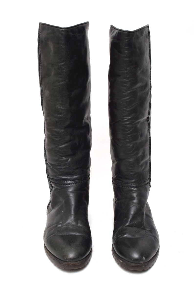May include: A pair of black leather knee-high boots with a pointed toe.