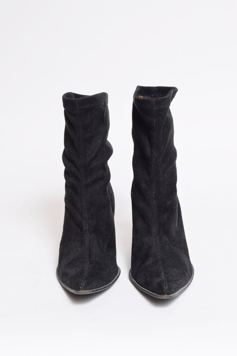 May include: A pair of black suede ankle boots with a pointed toe and a low heel.