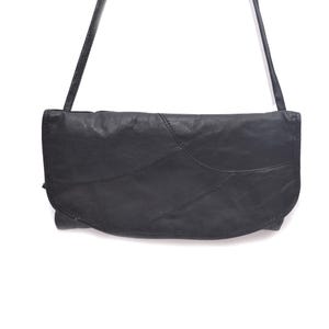 May include: Black leather shoulder bag with a long strap. The bag has a curved flap and a patchwork design. The bag is made of a soft, textured leather. The bag is a clutch style and is suitable for everyday use.