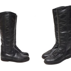 May include: A pair of black leather knee-high boots with a pointed toe and a low heel.