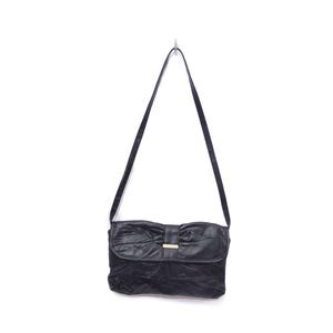 Może przedstawiać: Czarna skórzana torba na ramię z klapką w kształcie kokardy i długim, cienkim paskiem. Torba ma prostokątny kształt ze złotym zapięciem. Torba wisi na białym tle.