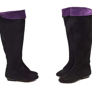 May include: A pair of black suede knee-high boots with purple suede trim at the top.