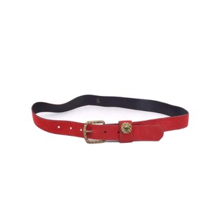 Può includere: Una cintura in pelle scamosciata rossa con una fibbia dorata e un design floreale decorativo. La cintura è larga circa 2,5 cm.