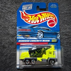 May include: A Hot Wheels Oshkosh Concrete Mixer toy car on its original blue and yellow packaging. The toy truck is yellow and black with silver wheels. The packaging includes the text "GUARANTEED FOR LIFE" and "COLLECTOR '863".