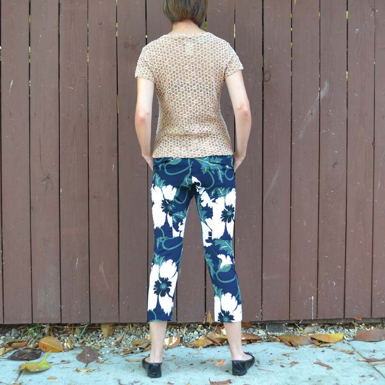 May include: A person wearing a beige crochet top and blue and white floral cropped pants.