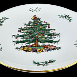 May include: White oval serving platter with a Christmas tree design. The tree is decorated with ornaments and presents are at the base. The rim has a gold trim and decorative accents.