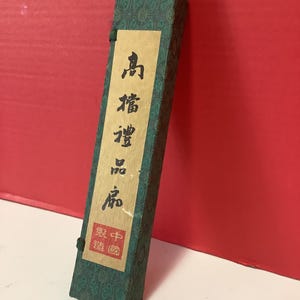 K&ouml;nnte beinhalten: Eine gr&uuml;ne Schachtel mit chinesischen Schriftzeichen auf einem Etikett. Das Etikett lautet "Qing-Dynastie" und "Hergestellt in China".