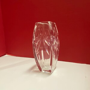 May include: A clear glass vase with a geometric pattern. The vase is rectangular in shape and has a square base.