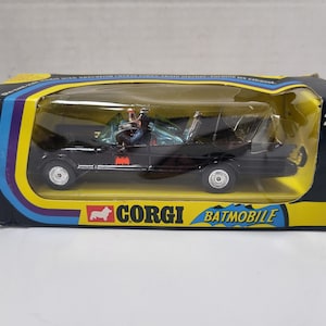 May include: A black Corgi Batmobile toy car in its original box. The car features the Bat symbol and is displayed in a clear plastic case. The box has a yellow and blue design with the number 267.
