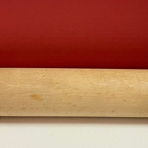 May include: A wooden rolling pin with a light brown color. The rolling pin has two handles on either end.