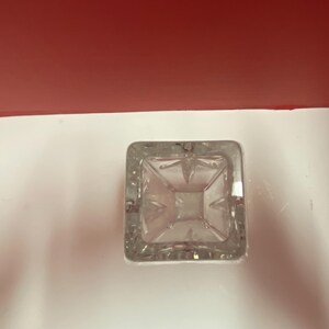 May include: A clear glass vase with a square base and intricate cut glass design.