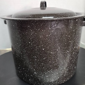 Może przedstawiać: Czarny emaliowany garnek do gotowania z białą, kropkowaną powierzchnią i pokrywką. Garnek ma jeden uchwyt na pokrywce.